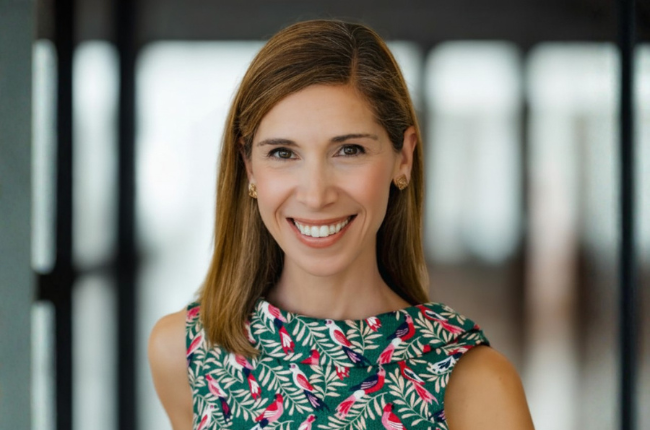 Kristel Bauer smiling in a floral-patterned dress in a professional headshot.