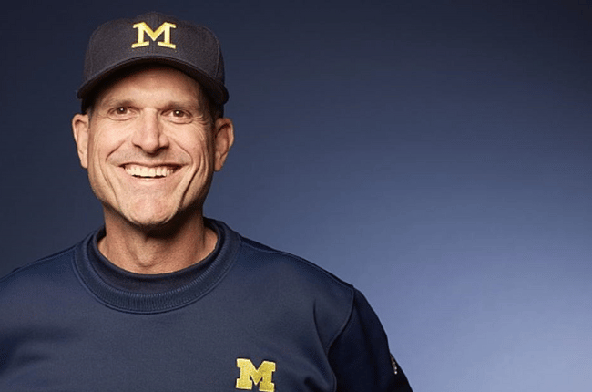 jim harbaugh posing in front of blue background