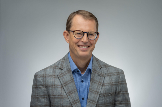 mike studeman pictured against a grey background smiling