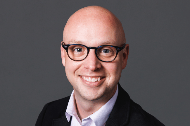 mark bryan pictured against a grey background smiling