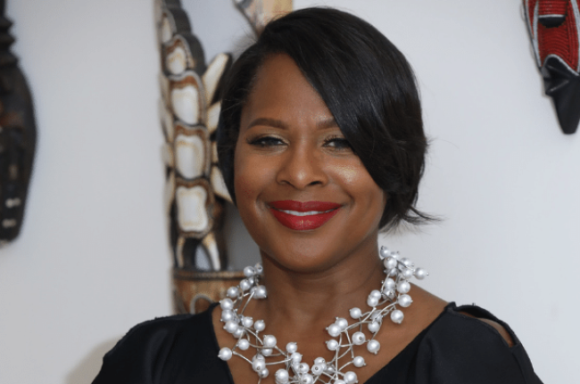 Joan Higginbotham smiling in a front of a decorated wall