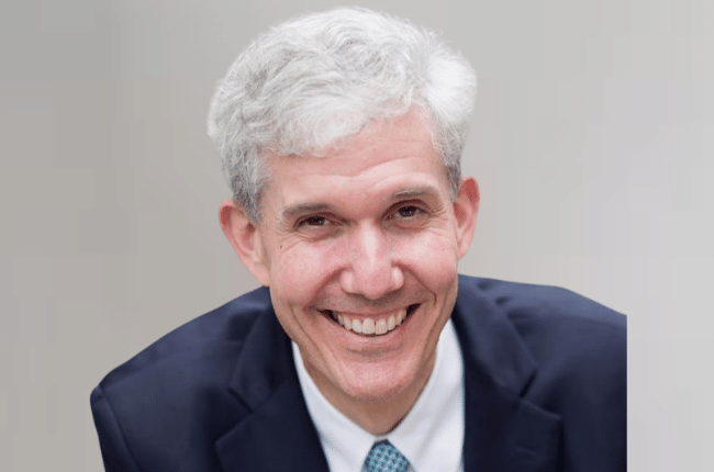 matthew slaughter smiling, wearing a suit and tie