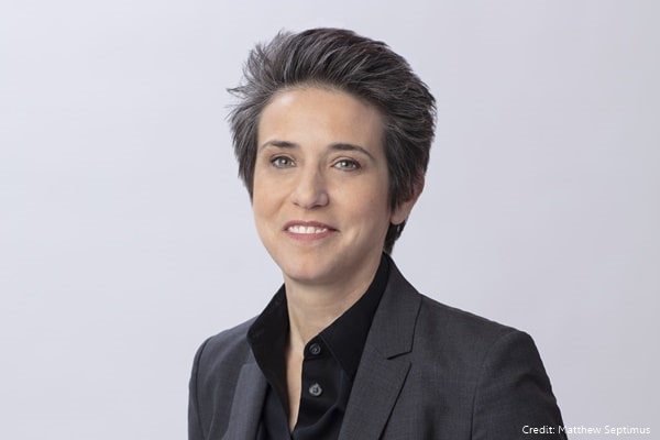 Amy Walter Smiling at the camera in a dark grey suit jacket and black collared shirt